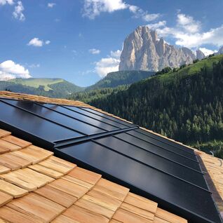Solarpaneele auf einem Holzdach mit einer beeindruckenden Berglandschaft im Hintergrund. Solarpaneele auf einem Holzdach mit einer beeindruckenden Berglandschaft im Hintergrund.