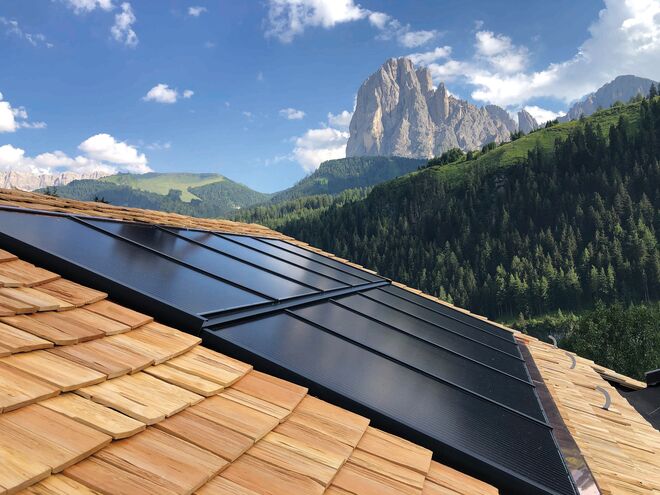 Solarpaneele auf einem Holzdach mit einer beeindruckenden Berglandschaft im Hintergrund. Solarpaneele auf einem Holzdach mit einer beeindruckenden Berglandschaft im Hintergrund.